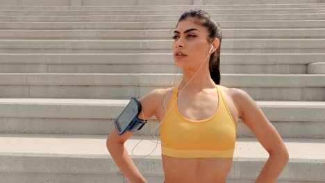 young female athlete with smartwatch and smartphone listening to music