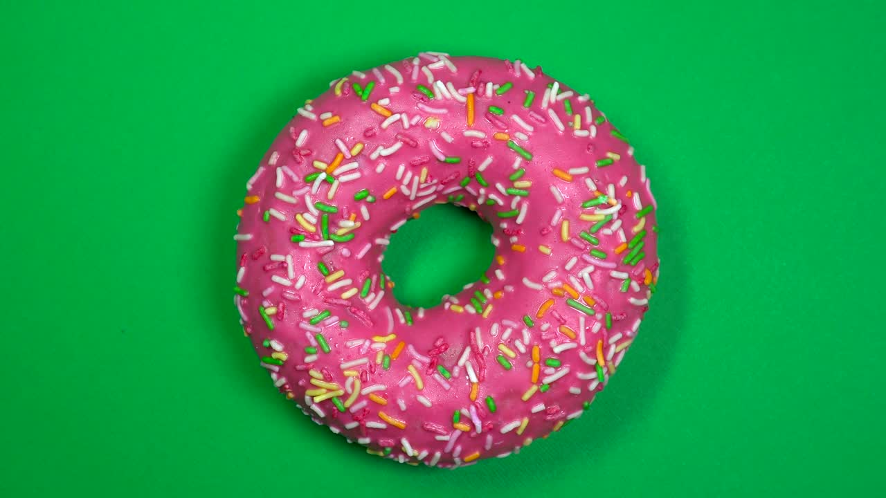 delicioso y fresco rosquilla de rosquilla macro disparo de primer plano girando sobre un fondo verde.