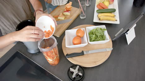 Young-woman-prepares-a-soup-with-fresh-carrots-and-oranges-on-a-modern-kitchen-counter