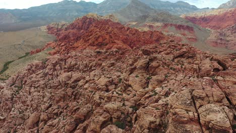 a bird's eye view of a red rocky mountain range with mountains in the background