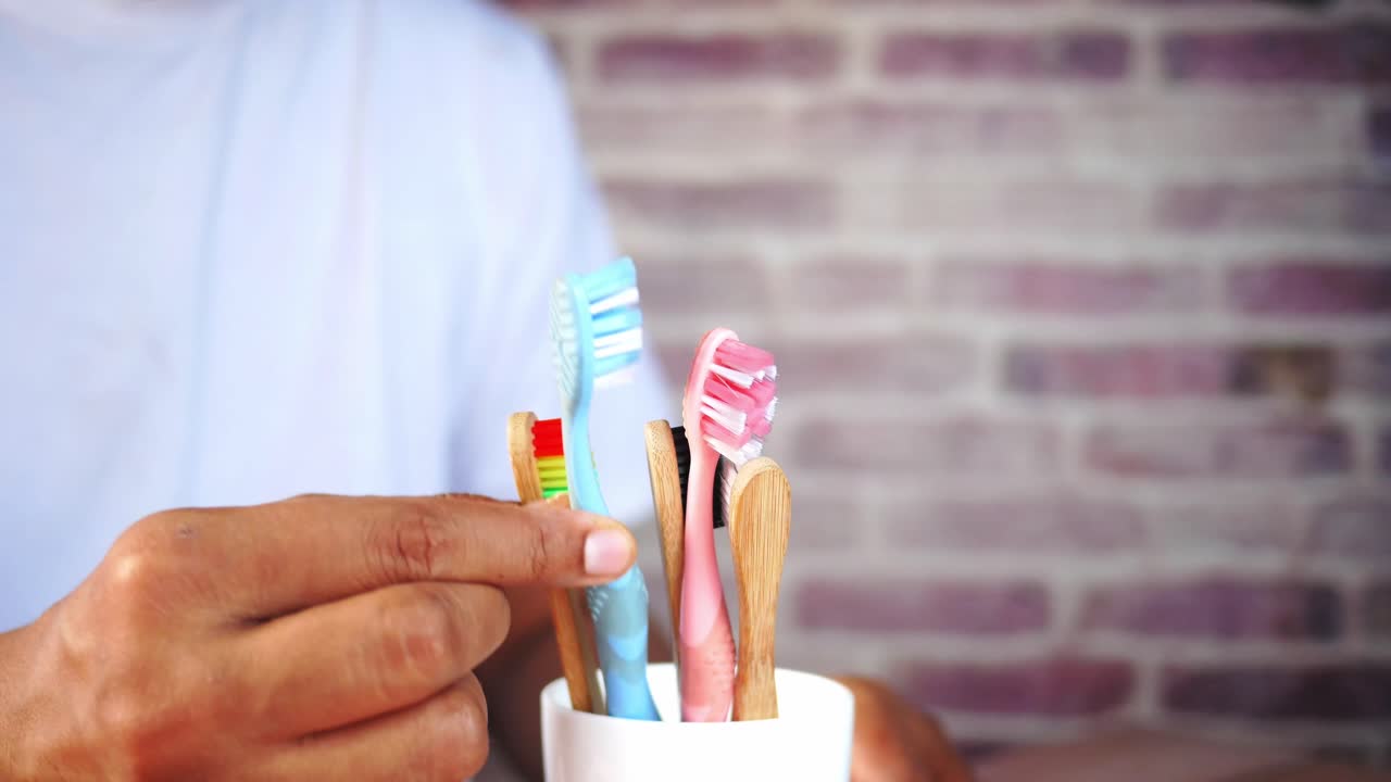 persona con cepillos de dientes en una taza