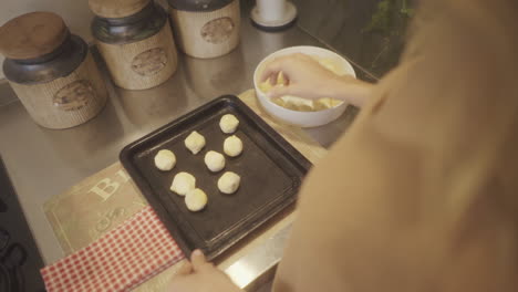 person preparing traditional chipa bread on a baking tray in a home kitchen, capturing the warmth and authenticity of homemade baking