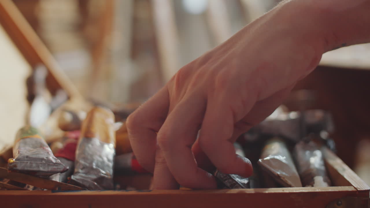 las manos del artista eligiendo la pintura