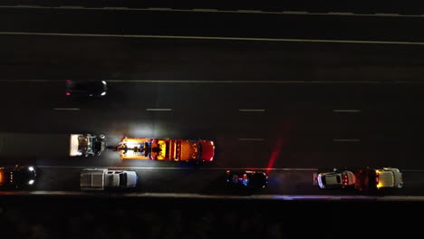 bird's eye view of towing service pulling a truck and stopping in stop lane on the highway at night