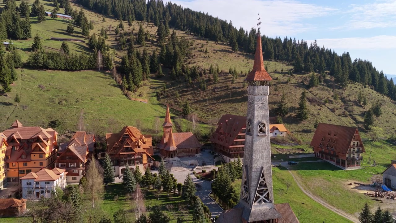 Veduta aerea con drone di un campanile tradizionale in legno con un'alta guglia e un orologio a Ciocanesti, Bucovina, Romania