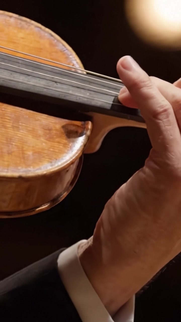 Una elegante actuación capturada continuamente: un primer plano del arte de la mano de un violinista mientras domina hábilmente las cuerdas en una melodía hipnotizante.