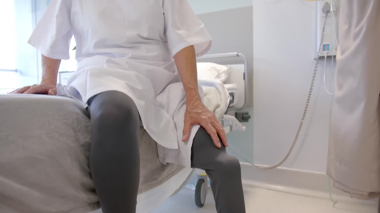 paciente mayor caucásica con pierna protésica sentada en la cama del hospital