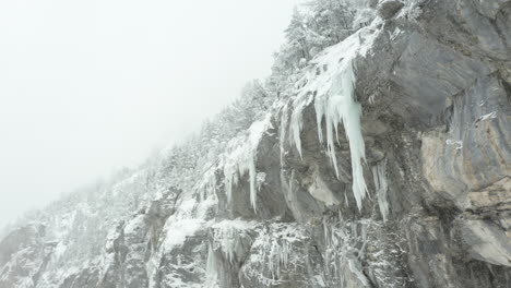 aerial reveal of large icicles hanging of mountain ridge