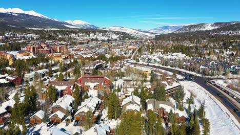 aerial drone view of cars driving through winter ski town with resort hotels and vacation rental homes for traveling through the mountains