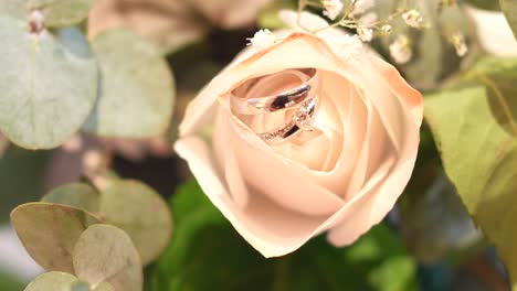 Bouquet-of-white-roses-with-wedding-rings-between-their-petals,-surrounded-by-eucalyptus-leaves-and-other-foliage