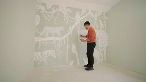 the artist is decorating walls by drawings in the children's room. art painting of the walls in the new house. repair works.