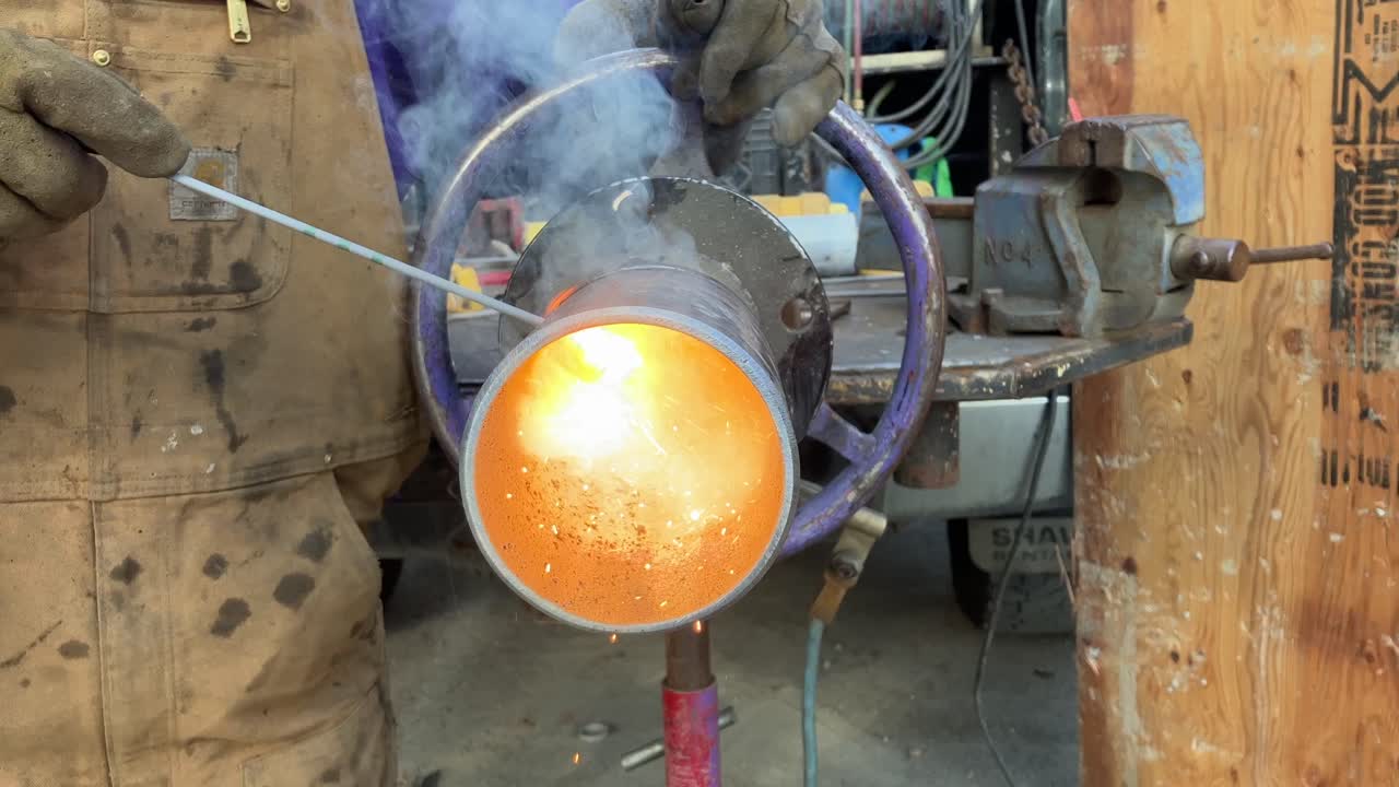Close-up shot of flames and sparks coming out of a metal pipe being welded
