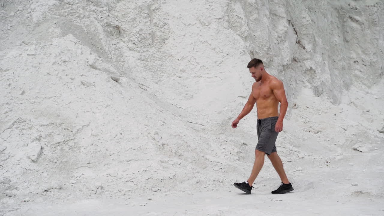 Sexy model posing on nature. Young shirtless athletic man walking on mountain