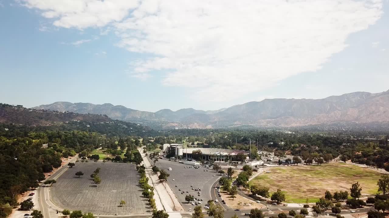 Rose Bowl football stadium in Pasadena at sunset time. Aerial approaching shot. Angeles national forest mountains in background. California, USA