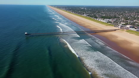 aerial view of a long sandy beach with a pier and coastal town