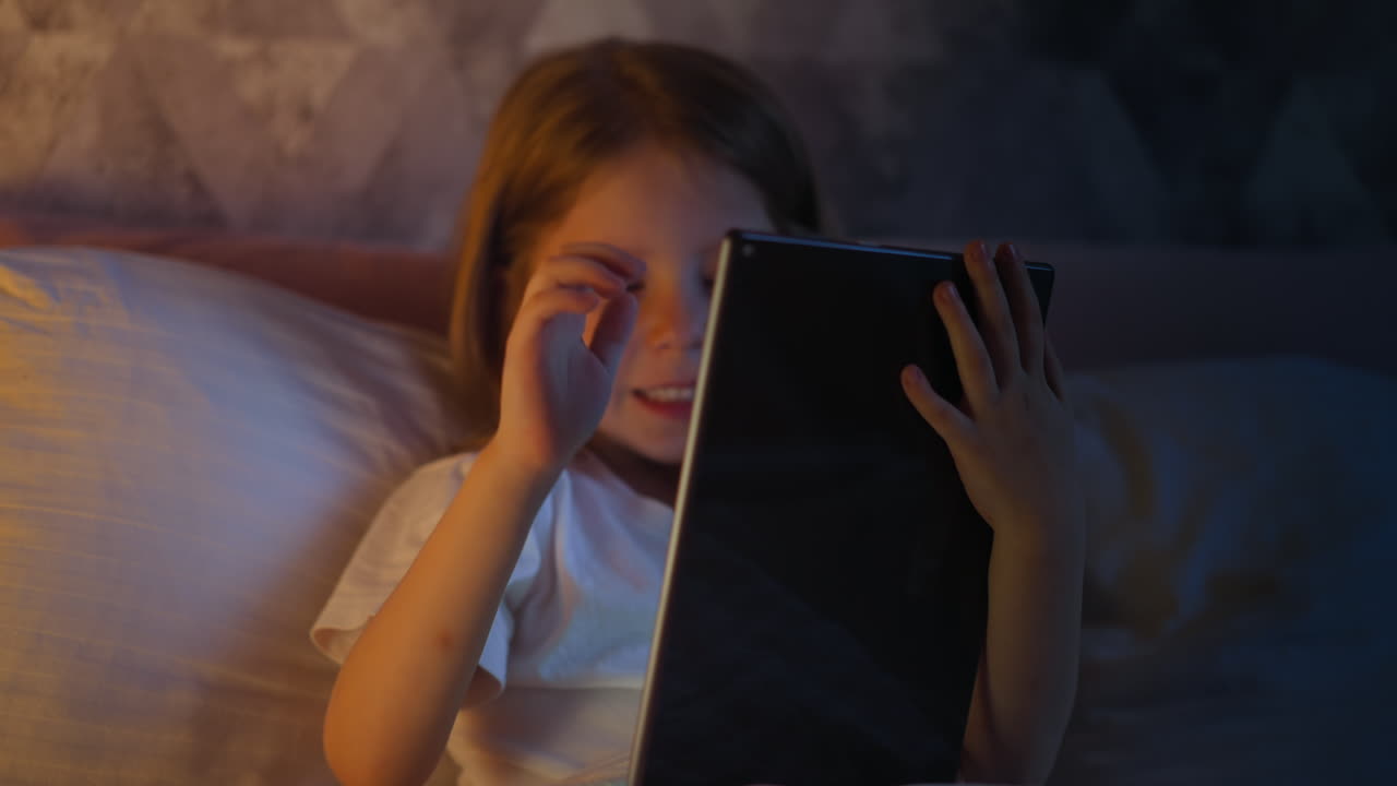 Cute little child celebrates win in videogame sitting on bed