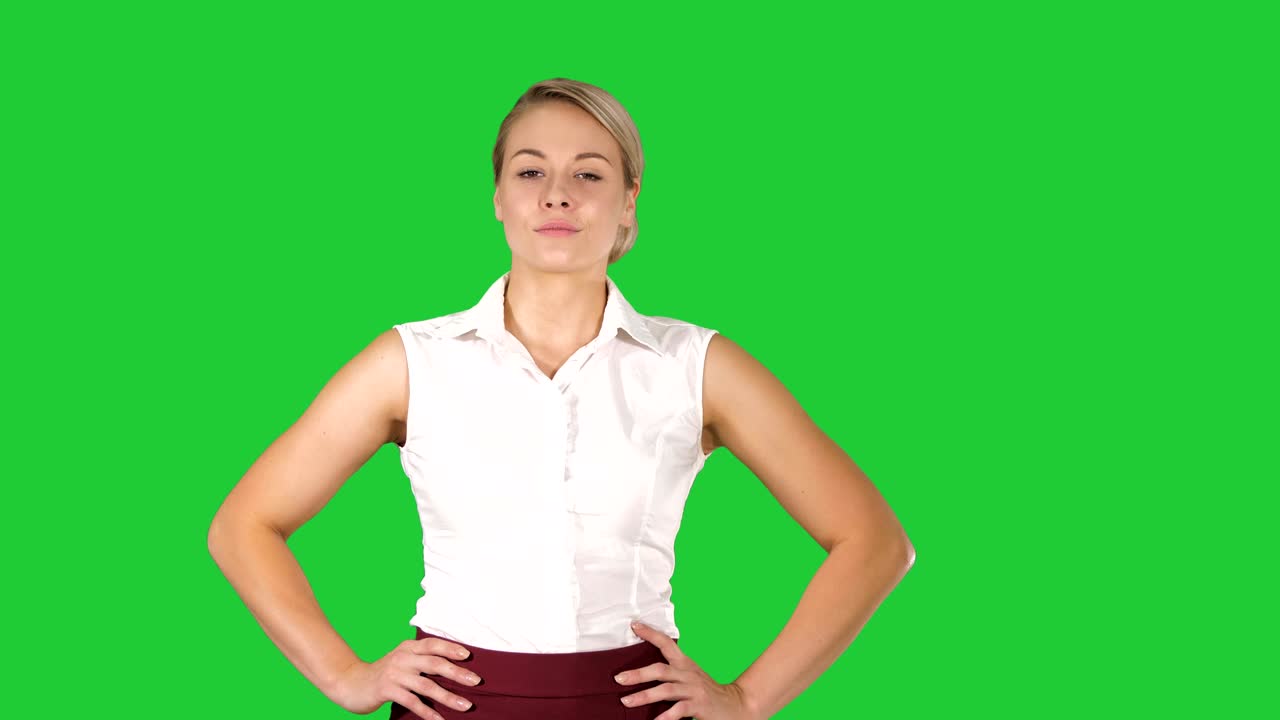 Selvsikker ung smuk servitrice går med hænderne i siden på en grøn skærm, Chroma Key.