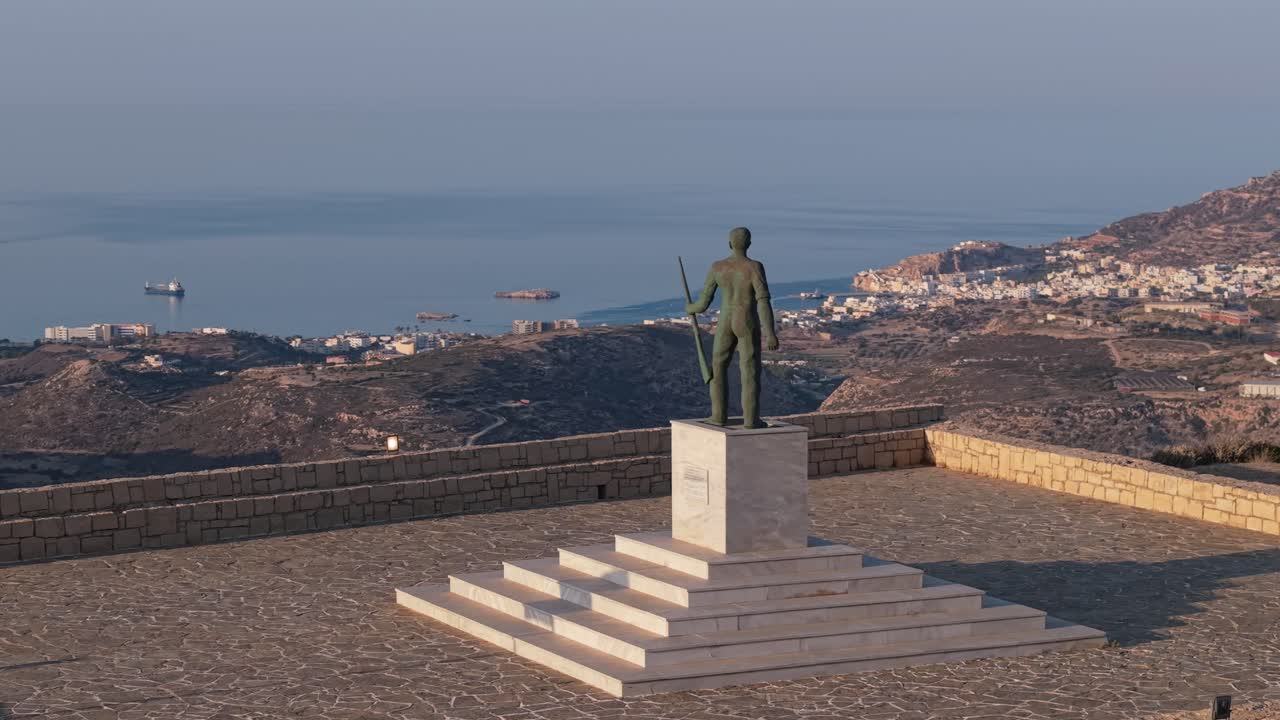 Karpathos manzarası ve Ege Denizi arka planda olacak şekilde, Yunanistan'daki asker heykelinin yörüngesinde dönen drone çekimi