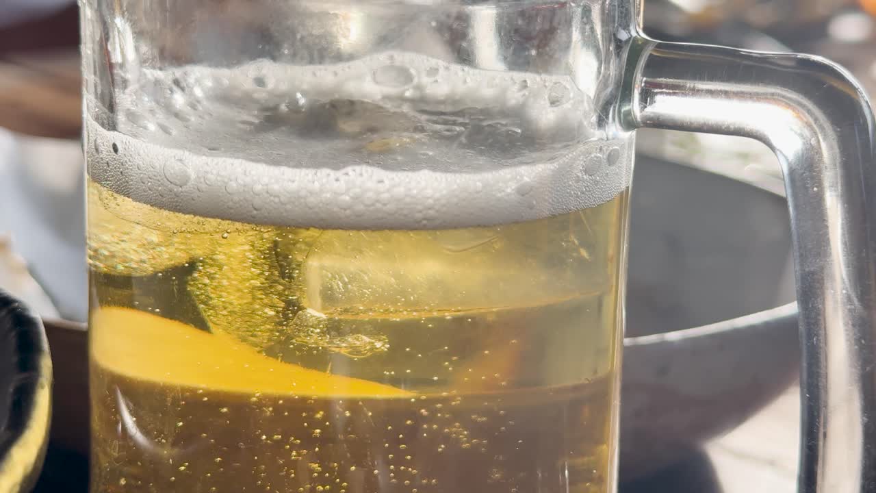 Close-up of a beer mug with rising bubbles, captured in natural sunlight at a beach club in Phuket