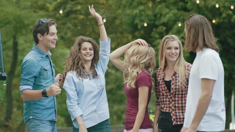 happy friends dancing, having fun and enjoying party outdoors.