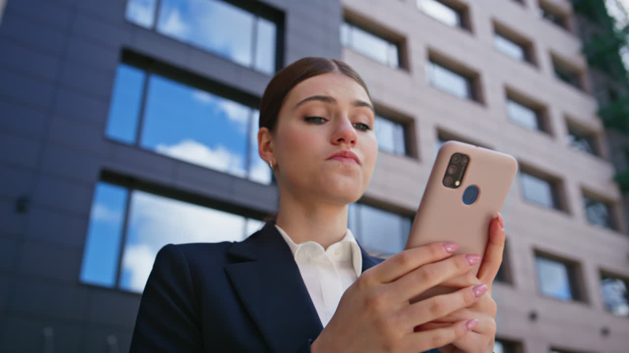 Shocked businesswoman reading cellphone message standing outside office closeup