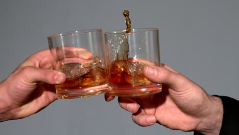 men clinking whiskey glasses on grey background