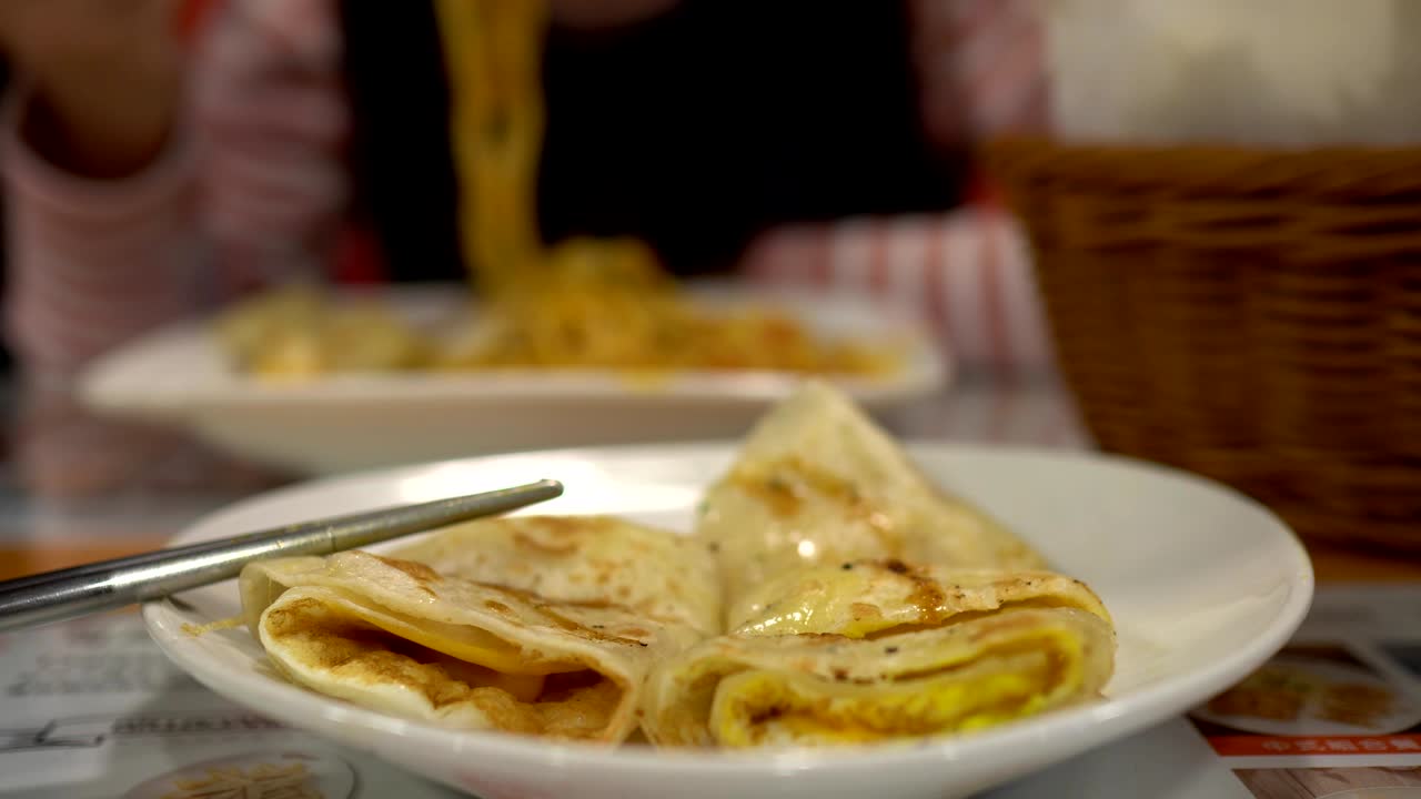 cerca de quiche en el restaurante. con palillos. el fondo borroso es una niña tomando una comida.