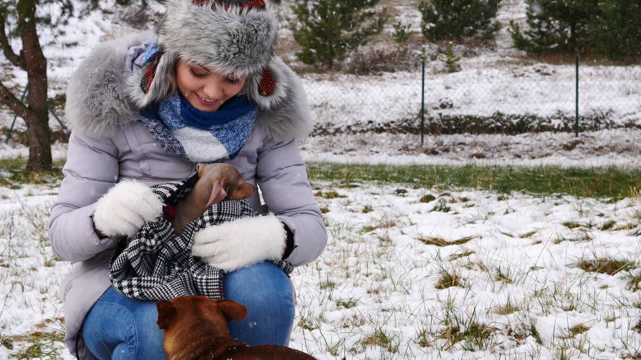 여자 는 겨울 밖 에서 작은 개 와 함께 놀고 있다