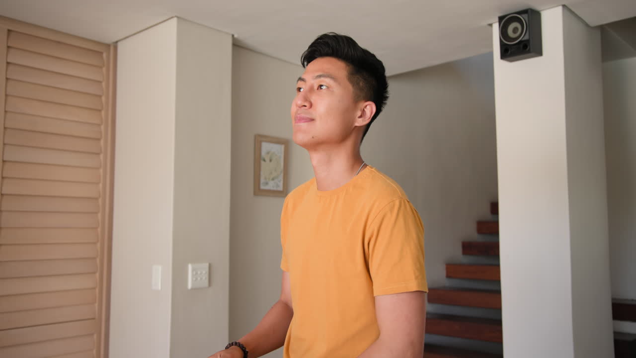 Young man in yellow shirt standing at home, looking thoughtfully ahead