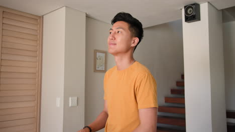young man in yellow shirt standing at home, looking thoughtfully ahead
