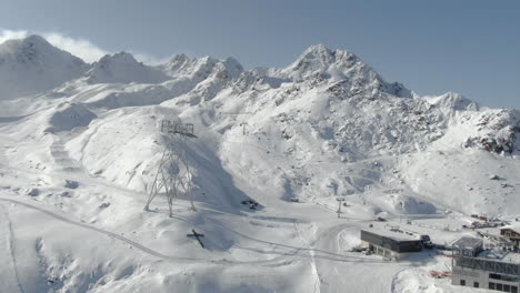cruz cristiana en el lado de la colina toma panorámica aérea de las montañas nevadas en la estación de esquí iluminada por el sol - kauntertal, austria