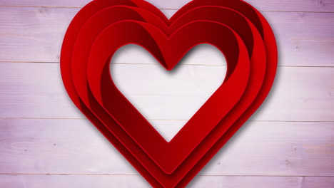 layered red heart shapes moving over wooden background