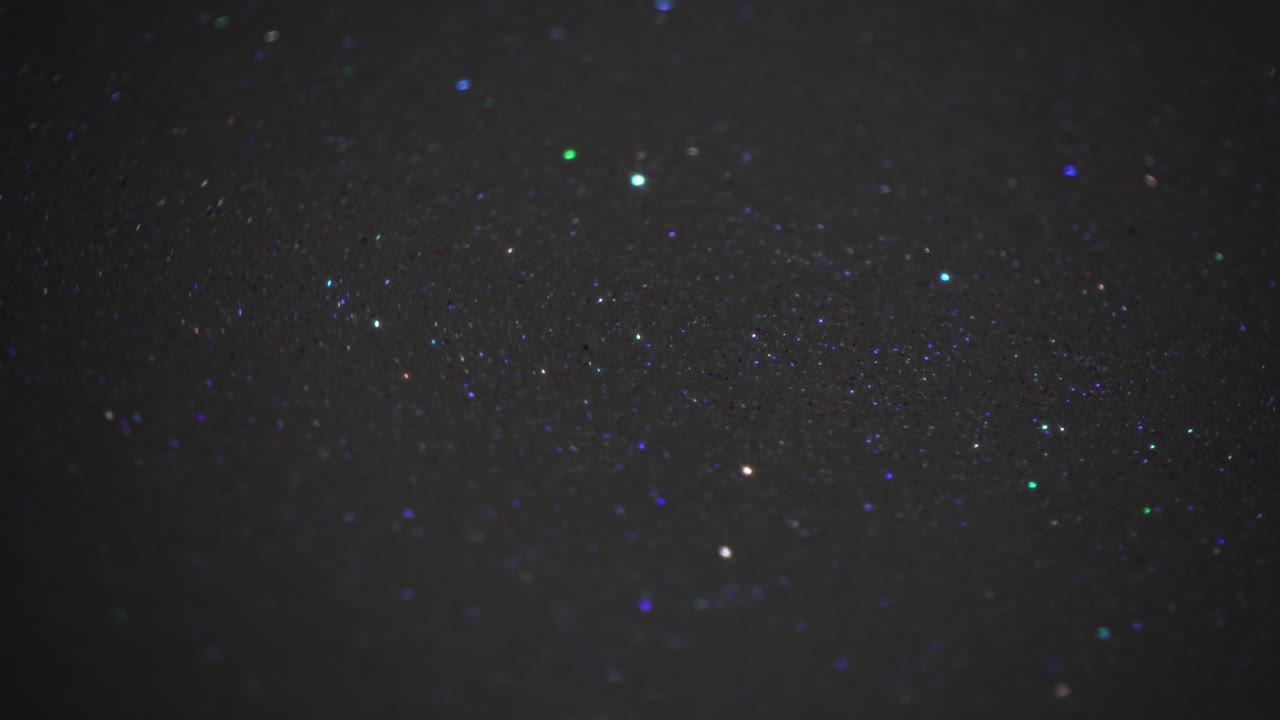 partículas de brillo de colores giratorias en la superficie oscura