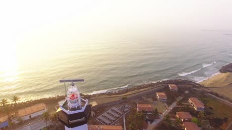 Drohnenaufnahmen,-Die-Auf-Einen-Leuchtturm-Mit-Blick-Nach-Unten-Fliegen,-Mit-Einem-Strand-Am-Frühen-Morgen-Im-Hintergrund