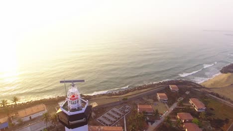 imágenes de drones volando hacia una casa de luz con un movimiento de mirada hacia abajo con la playa temprano en la mañana en el fondo