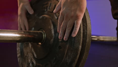 man powerlifter putting pancakes on bar in bodybuilding training in gym