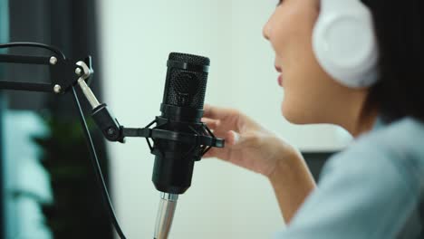 micrófono de condensador de primer plano del creador de contenido mujer anfitriona transmitiendo su podcast en portátil con auriculares conversación de entrevista en el estudio de transmisión en casa. blogger grabando voz por radio.