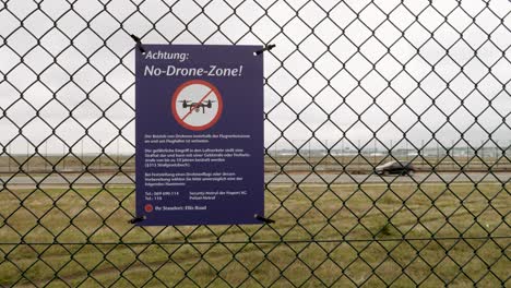 no drone zone warning sign on a fence at an airport