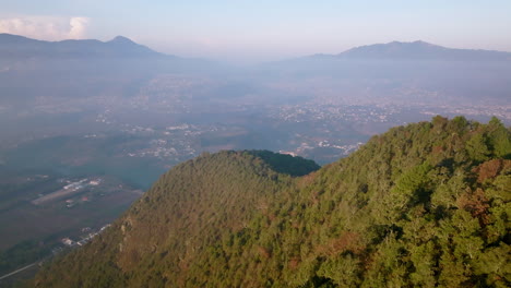 aerial flyover over the ridges of a mountain revealing the city of san juan osctuncalco in the morning light