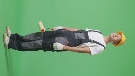 full body of side view asian man painter wearing safety helmet standing and look around in the green screen background studio
