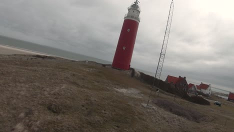 eierland lighthouse on grass-topped dunes at the village in coast of texel island in north holland, netherlands. - drone, pov fpv