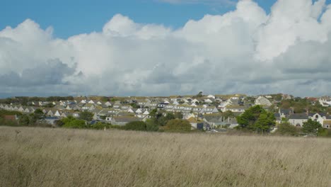 Toma-Panorámica-Del-Paisaje-Cinematográfico-De-4k-De-Nubes-Gigantes-Que-Se-Ciernen-Sobre-Un-Pequeño-Pueblo-Isleño,-En-Portland,-Dorset,-En-Inglaterra,-En-Un-Día-Soleado