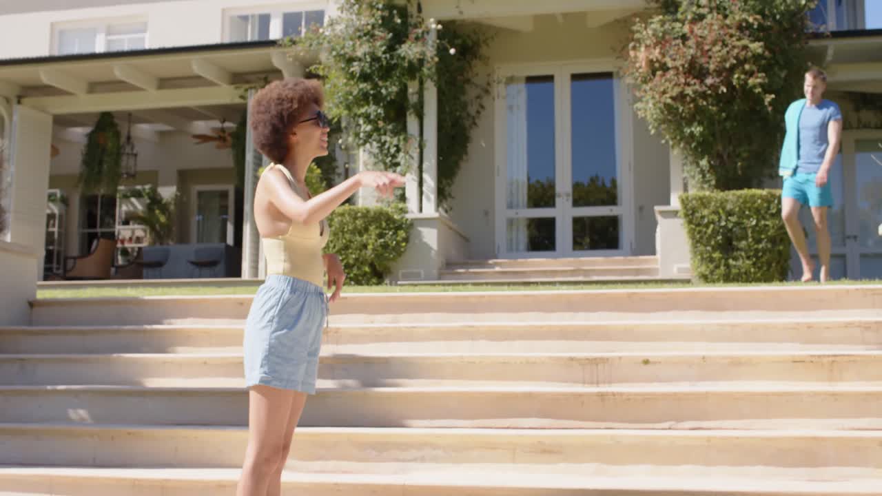 un grupo feliz y diverso de amigos agitando las manos y sosteniendo equipos de piscina en verano.