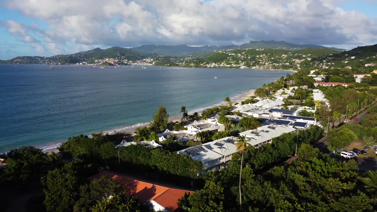 Establishing aerial of beachfront vacation property overlooking ocean bay and houses on hills in 4K