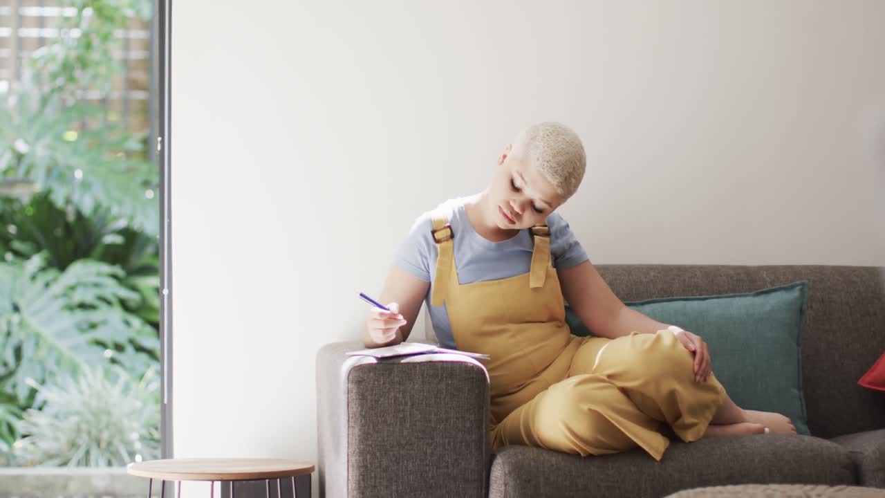 슬로우 모션으로 소파에 앉아서 메모를 하는 행복한 두 인종 여성