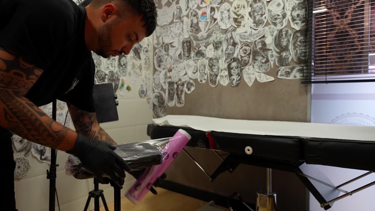 Artist male preparing a tattoo session covering a seat with plastic film