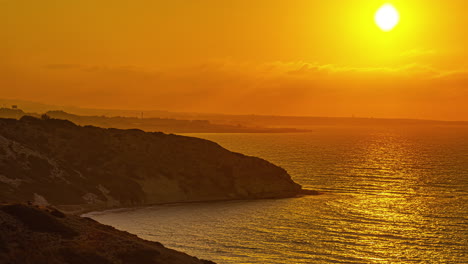 Timelapse-De-Una-Puesta-De-Sol-Dorada-Sobre-La-Costa-De-Un-Mar-Y-El-Acantilado