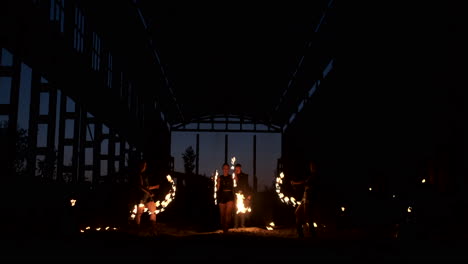 a group of people with fire and torches dancing at sunset in the hangar in slow motion. fire show.