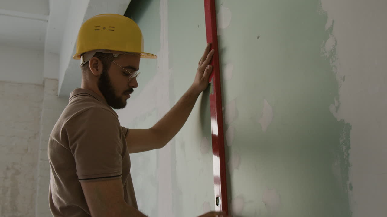 Construction worker using a level on a wall