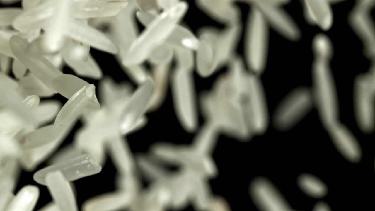 Chicchi di riso bianco che cadono al rallentatore su sfondo nero